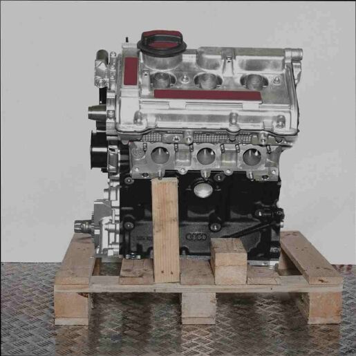 Seitenansicht eines AQD Motors auf einer Holzpalette vor weißem Hintergrund. Der Motorblock ist schwarz, die Anbauteile silberfarben.