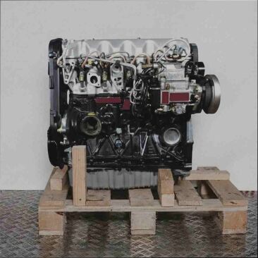 Motor AUF auf Holzpalette vor weißem Hintergrund. Dieses Bild zeigt einen einzelnen Motor, bereit für den Transport.