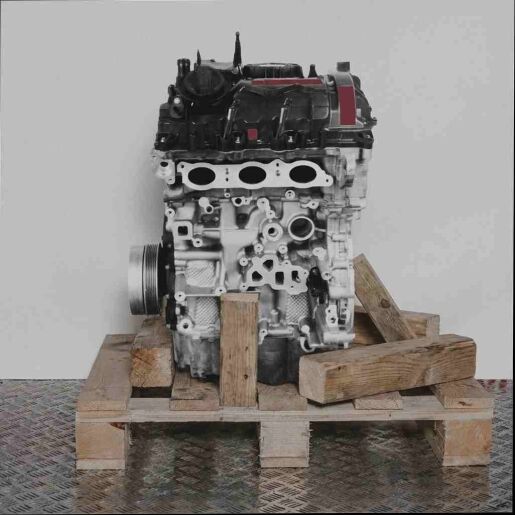 Seitenansicht eines Motors B38 A15 A auf einer Holzpalette vor weißem Hintergrund. Der Motor ist vertikal ausgerichtet.