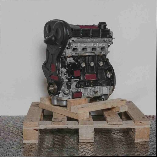 Seitenansicht eines schwarzen C 16 XE Motors auf einer Holzpalette vor weißem Hintergrund. Der Motor ist vertikal ausgerichtet.