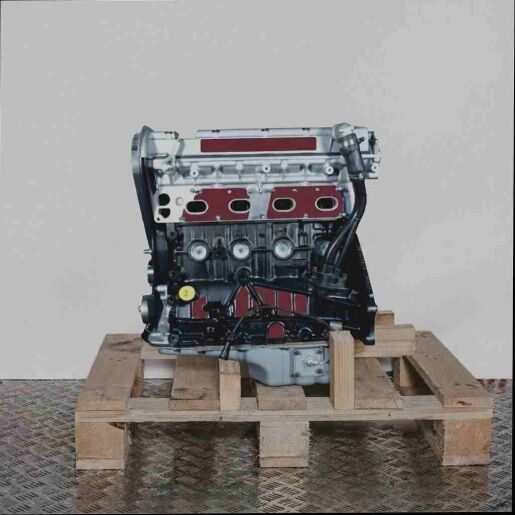 Seitenansicht eines C 20 XE Motors auf einer Holzpalette vor weißem Hintergrund. Der schwarze und silberne Motor ist vertikal ausgerichtet.
