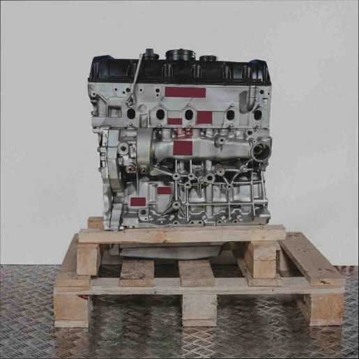 Motor vom Typ D auf Holzpalette vor weißem Hintergrund. Vertikale Aufnahme des Motors.