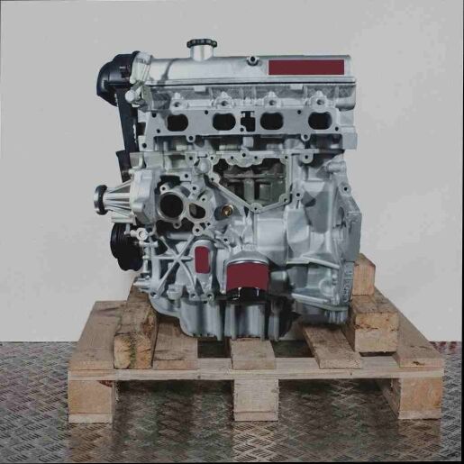 Silberner Automotor FYDB auf Holzpalette vor weißem Hintergrund. Der Motor ist vertikal ausgerichtet.