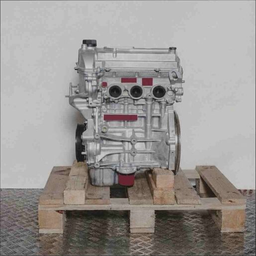 K10B Automotor auf Holzpalette vor weißem Hintergrund. Seitenansicht des Motors, leicht schräg von vorne oben.
