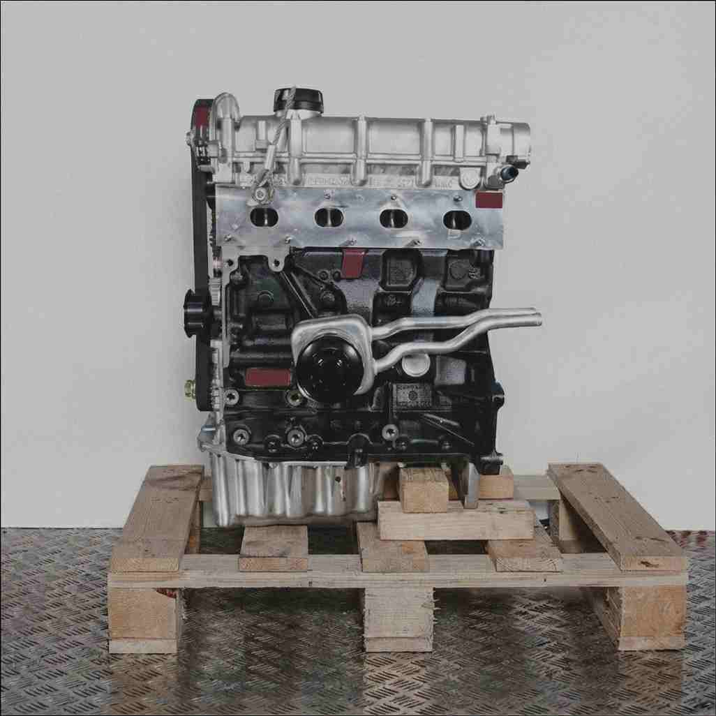 Automotor BAD auf Holzpalette vor weißem Hintergrund. Schwarzer Motorblock, silberner Zylinderkopf. Seitenansicht.