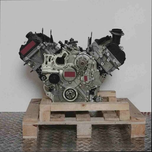 V-förmiger Motor CLAA auf Holzpalette vor weißem Hintergrund. Der Motor ist vollständig sichtbar und aus der Seitenansicht aufgenommen.